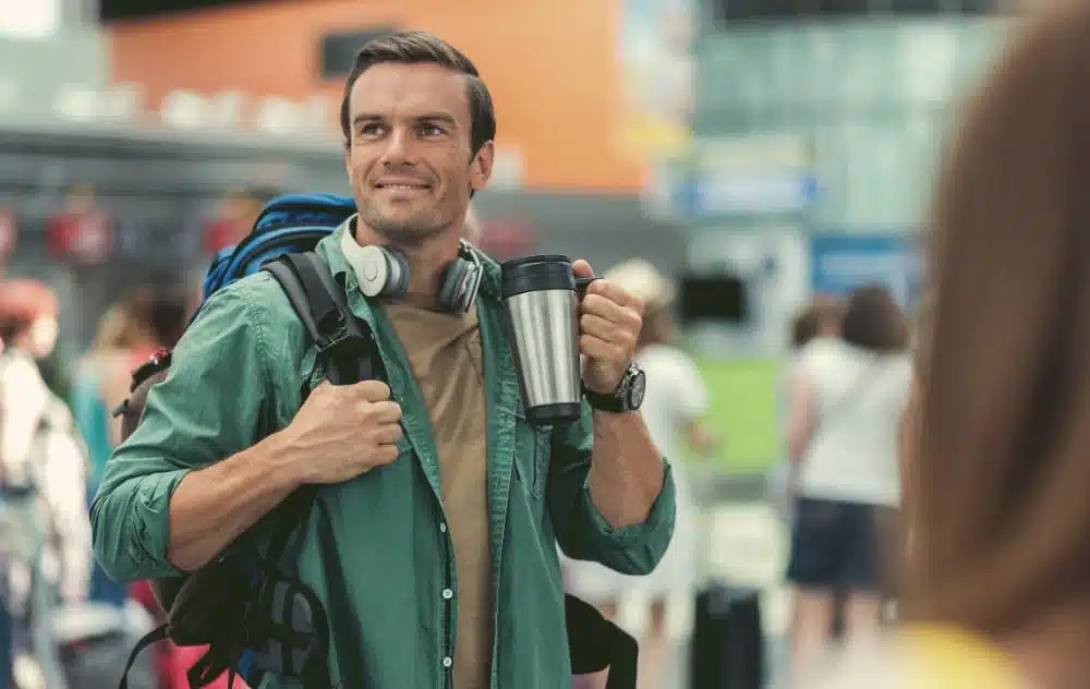 Man at airport with travel coffee mug