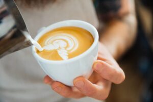 A Barista Pouring Frothed Milk into a Coffee