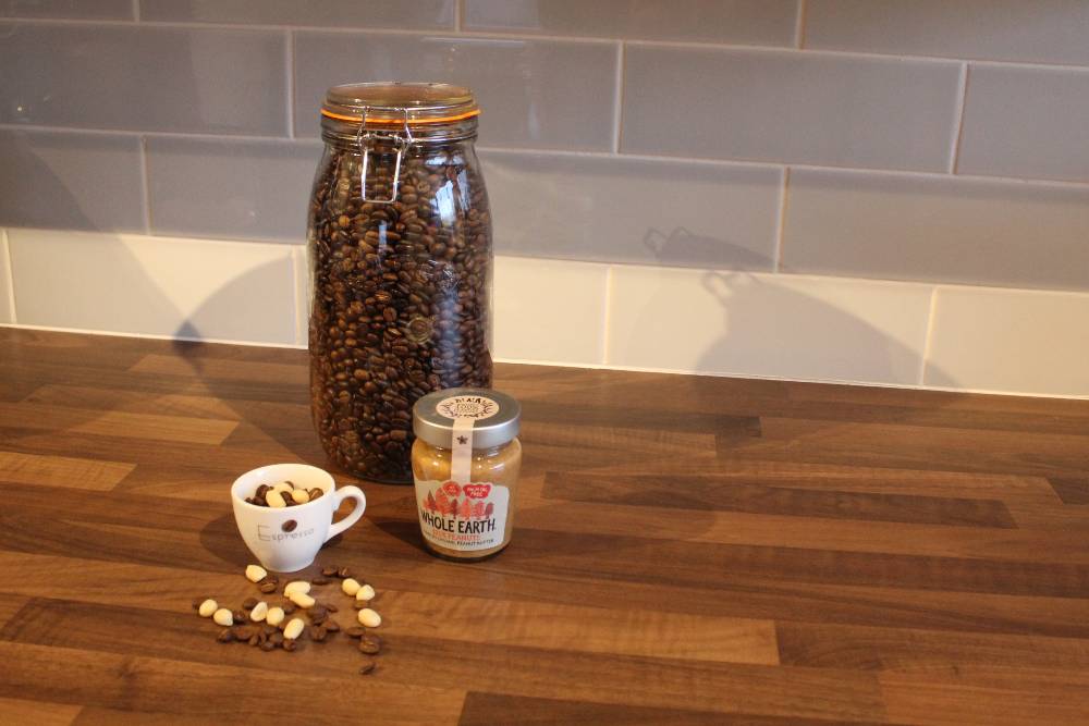 A big jar of coffee beans, peanuts, and peanut butter