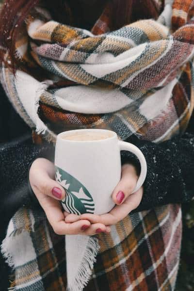 A person holding a big starbucks mug