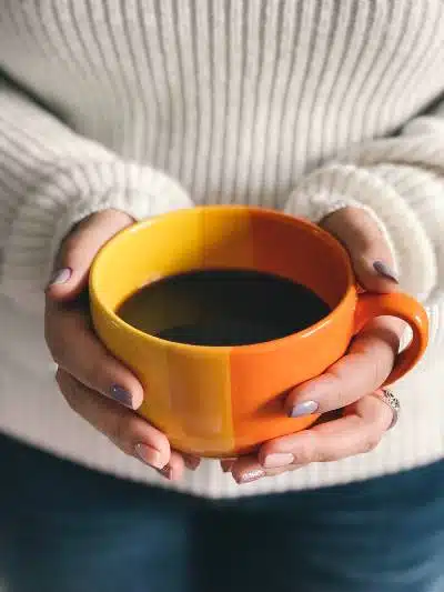 a lady holding a big mug of black coffee