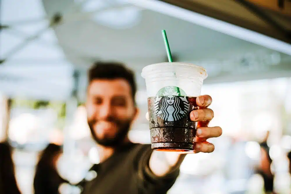 A guy holding a cool iced starbucks coffee