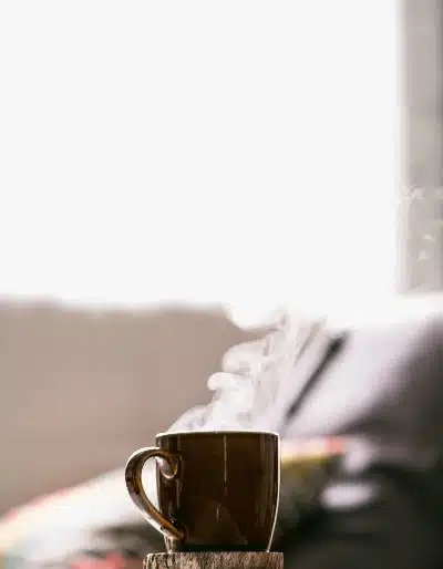 A steaming mug of coffee in front of a couch