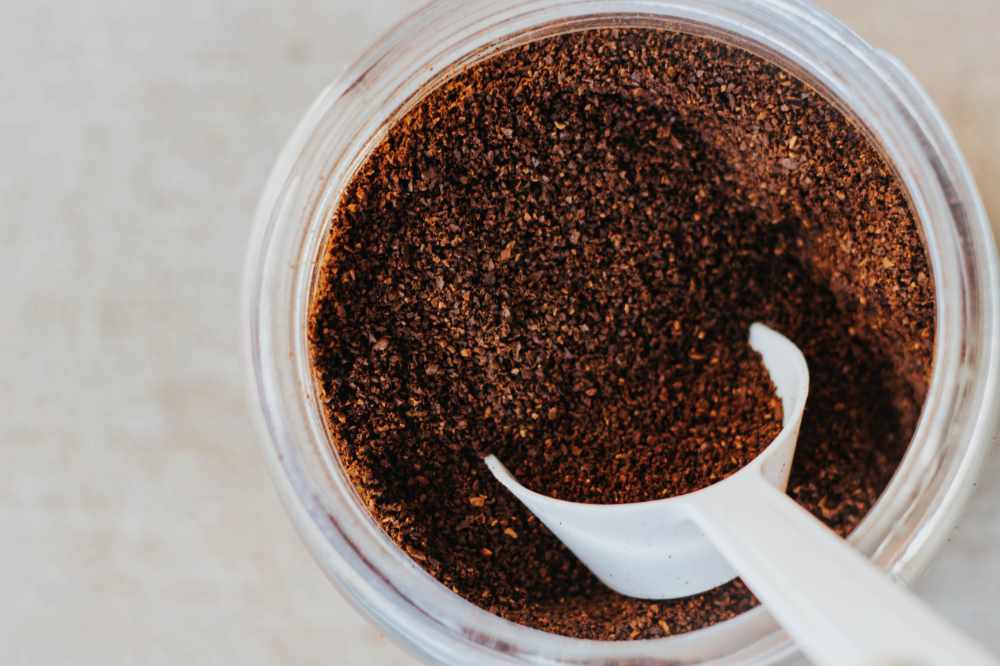 A jar of ground coffee with a scoop in it