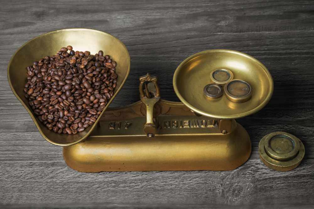 Coffee beans being weighed out on an old fashoned set of brass scales