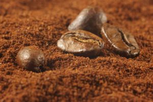 Some coffee beans amoungst lots of ground coffee