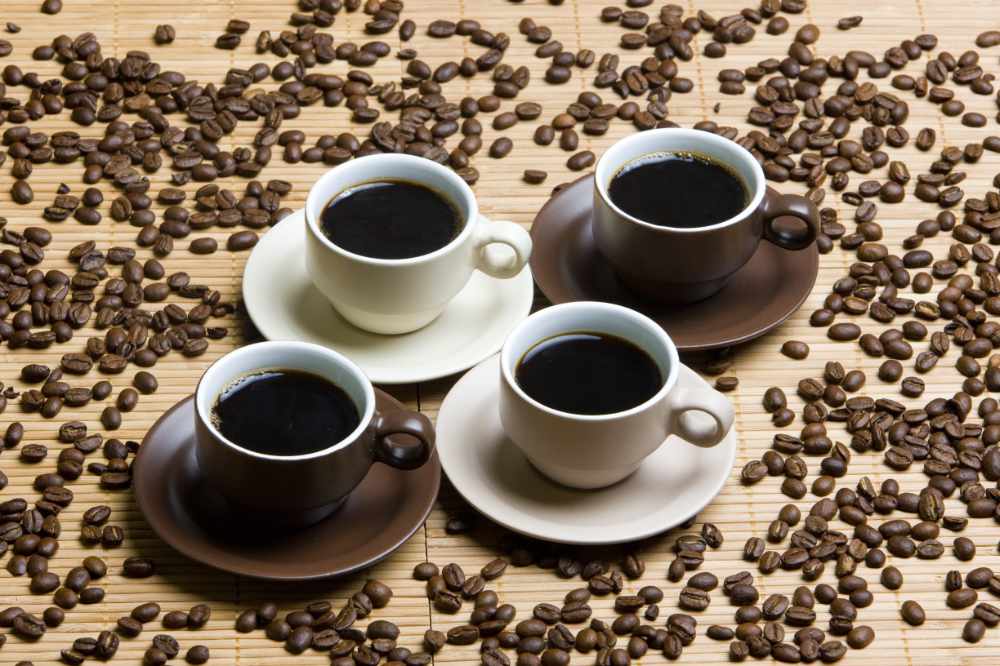four cups of coffee with coffee beans scattered around