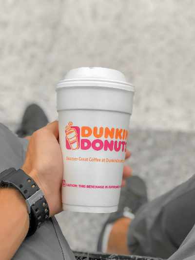 A hand holding a dunkin donuts coffee cup