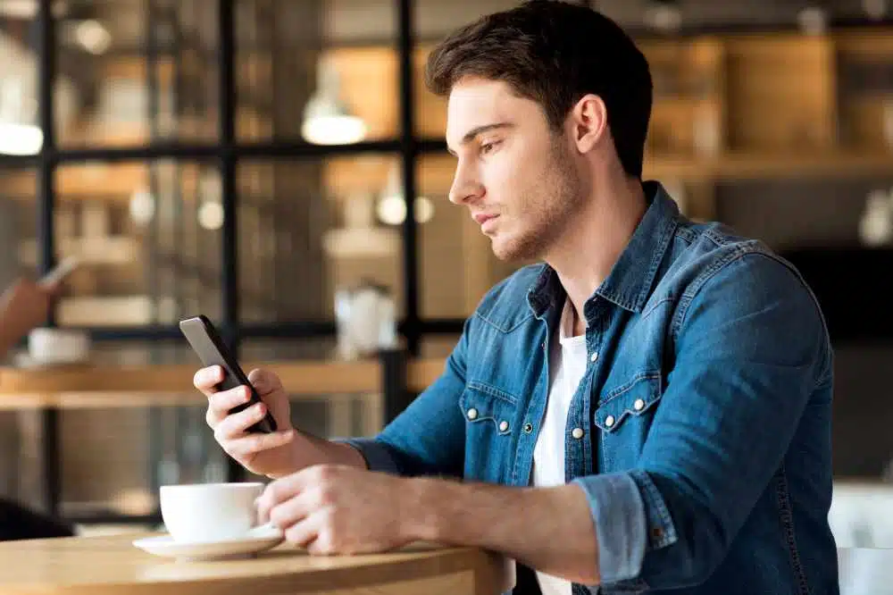 A man using his smartphone while enjoying a coffee