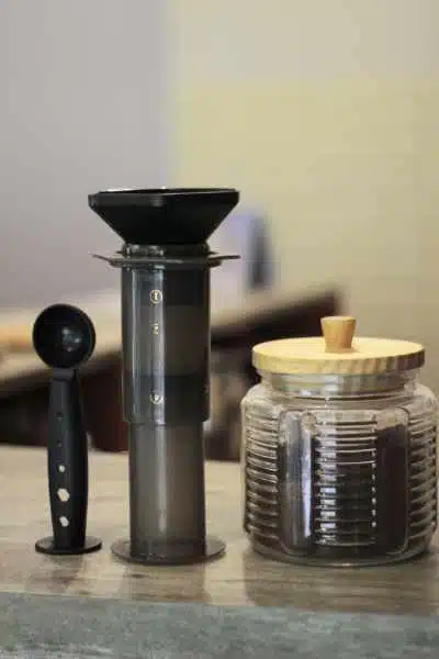 an aeropress with a scoop and jar of coffee