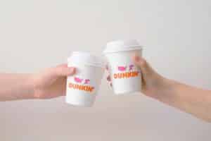 two people clinking their dunkin donuts coffee cups