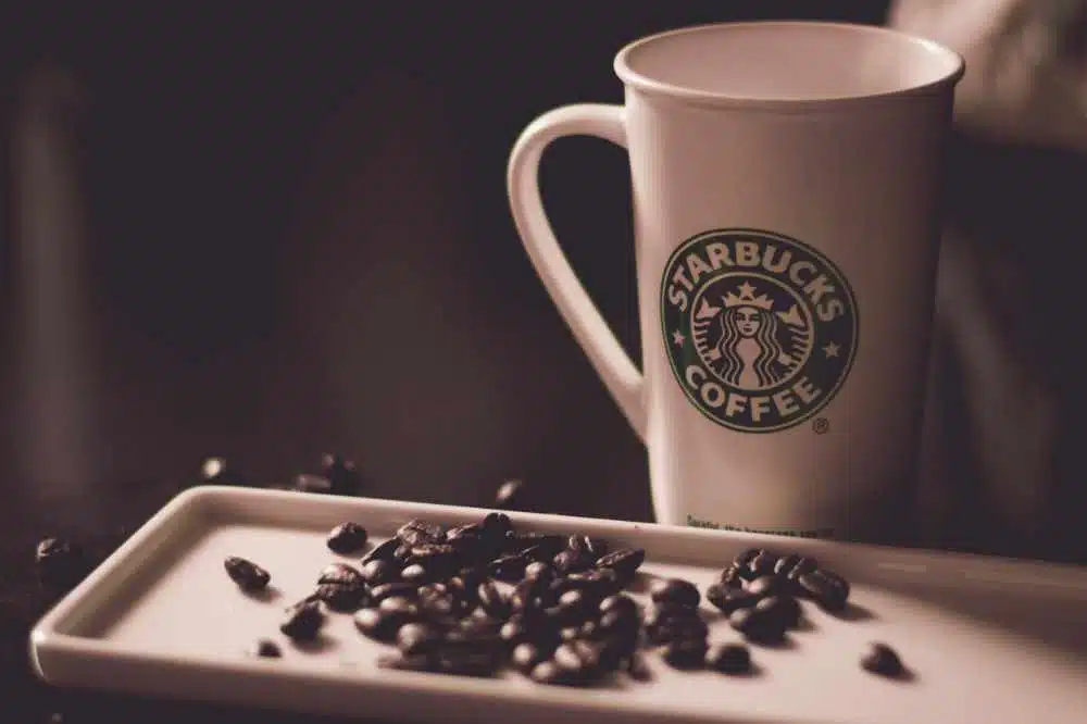 A Starbucks mug beside some coffee beans