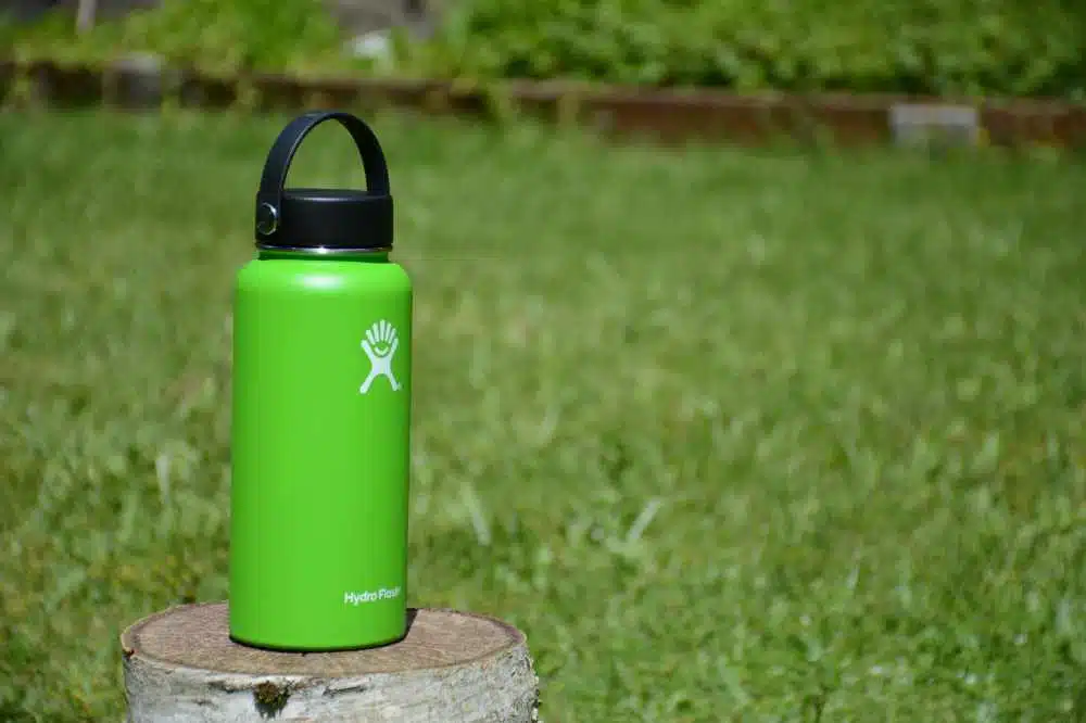 a hydro flask for coffee sitting on a stump
