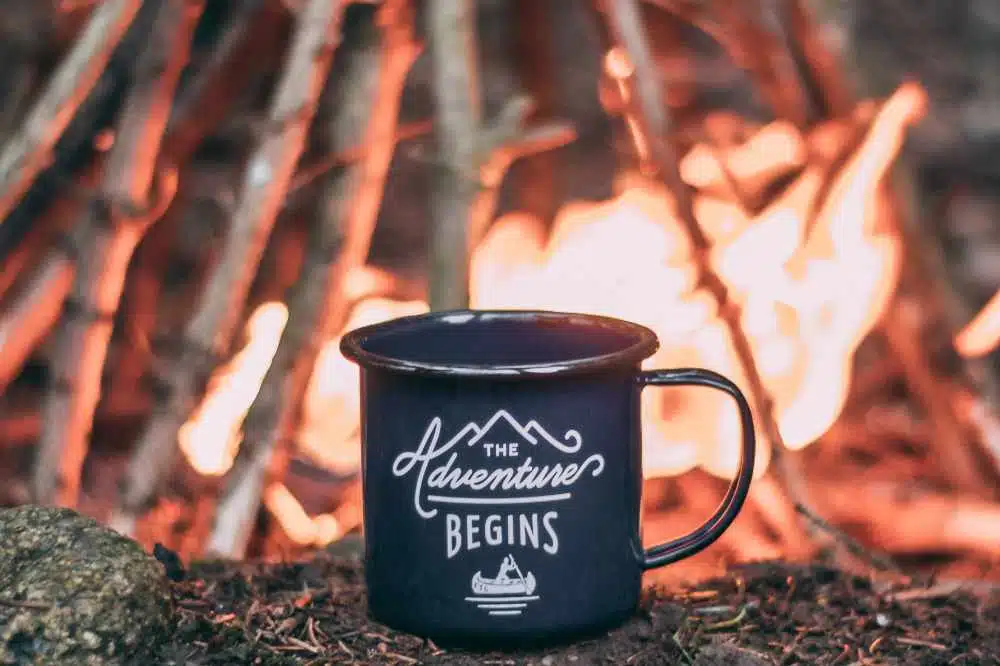 A mug of cowboy coffee sitting by a camp fire