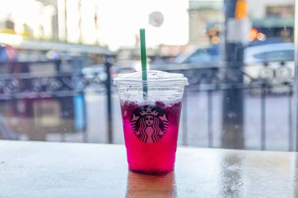 A pink starbucks drink on a table (ised dragonfruit lemonade)