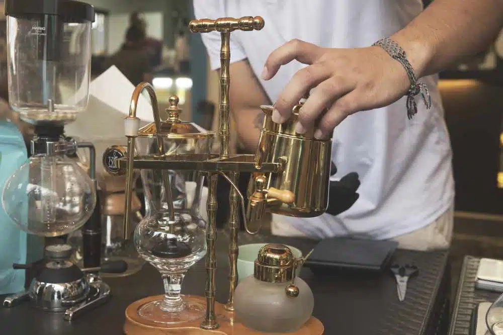 A barista using a belgian balance coffee syphon