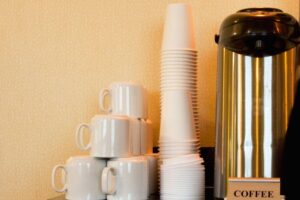 A coffee urn beside coffee cups