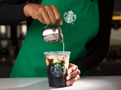 Starbucks employee pouring vanilla sweet cream into a to go cold brew cup