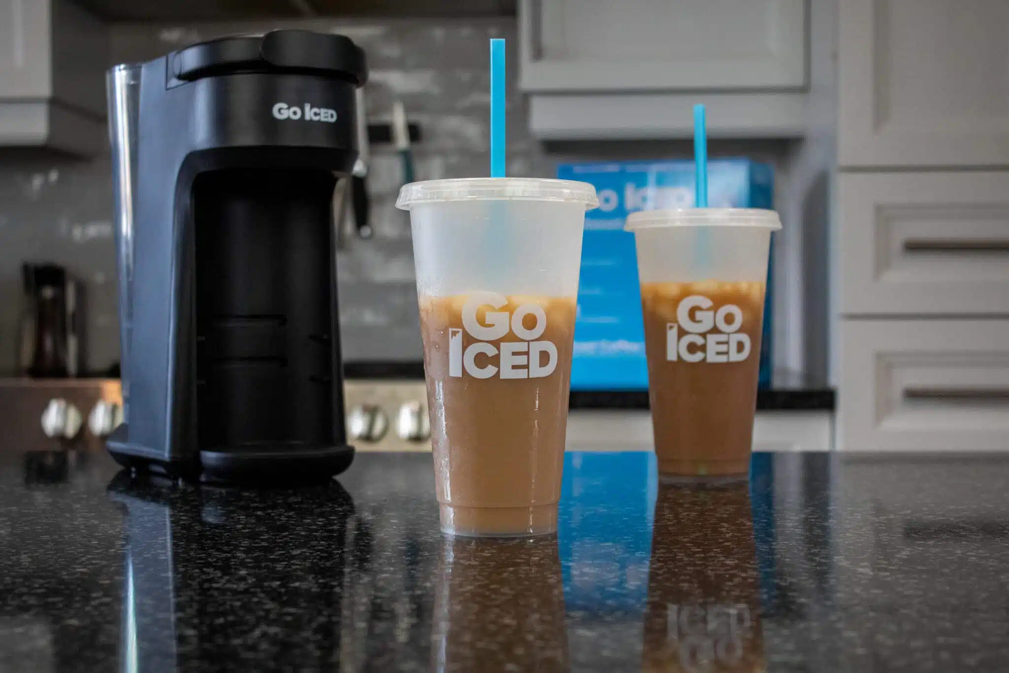 image of the go iced machine sitting on our counter top with two cups that have cold brewed coffee, ice and milk in them.